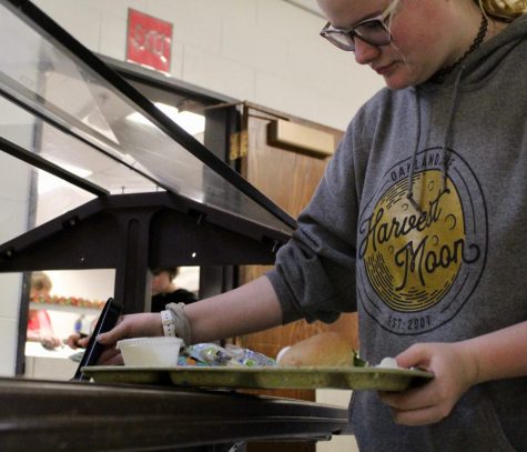 Freshman Reagan Wilson puts food from the salad bar onto her tray at lunch. Students noticed less salad bar options this week due to supply chain issues.