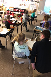 Senior Isaiah Daniell assists a second-grader with her reading assignment.  Daniell spends the last three class periods of every day at Yutan Elementary for his internship.