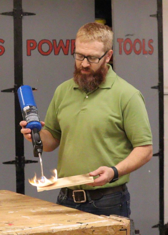 Shop teacher Brandon Thoene uses a torch to make a burnt wood finish. 