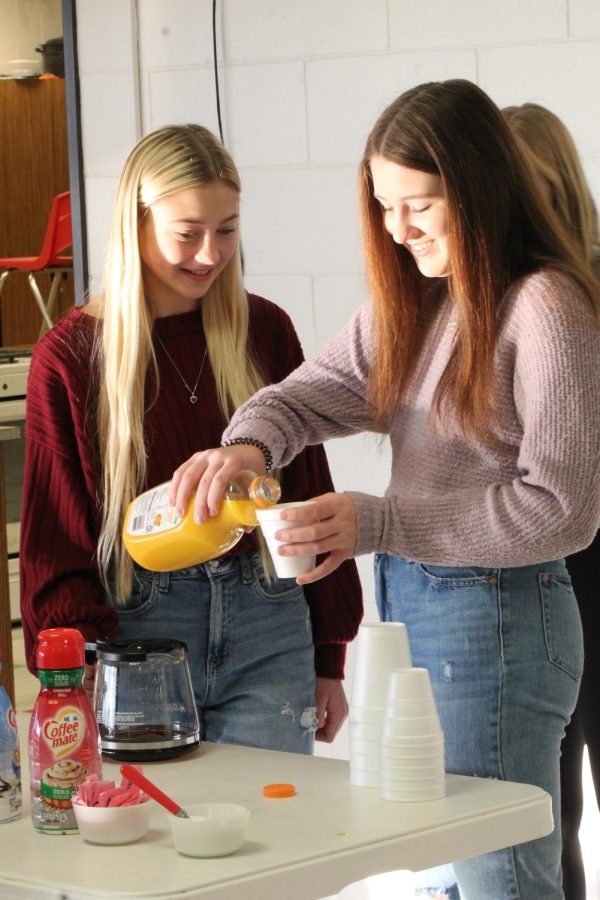 Senior Mallory Zeleny and sophomore Loganne Barta smile as they prepare breakfast for the Veterans Day program. The student council members help out every year with the program.
