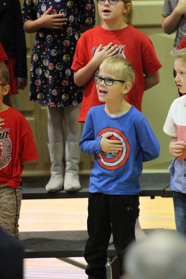 First-grader Colton Gale puts his hand over his heart while singing the Pledge of Allegiance. The first graders are included in the Veterans Day program every year. 