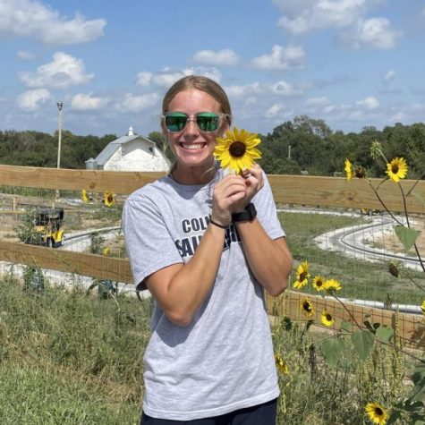 Senior Shaylynn Campbell poses with a sunflower at Valas Pumpkin Patch. Campbell enjoys the apple orchard the most. I love getting to go somewhere with my family to celebrate the fall, Campbell said. 