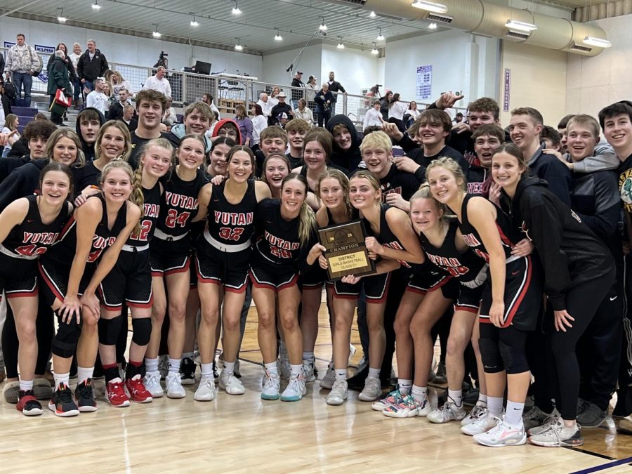 The Yutan girls basketball team and Yutan student section pose with the district championship plaque. After every win, the team and student section sing the school song, Hail Varsity.