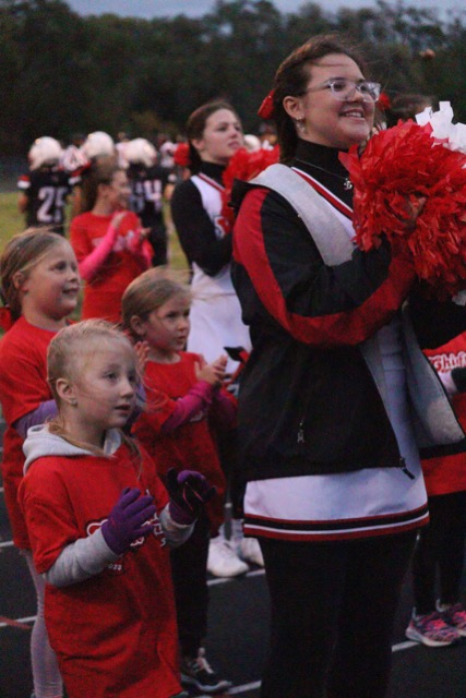During the football game, sophomore Lexi Bisaillon cheers with a camper. The cheerleaders and campers cheered together during the first quarter of the football game.