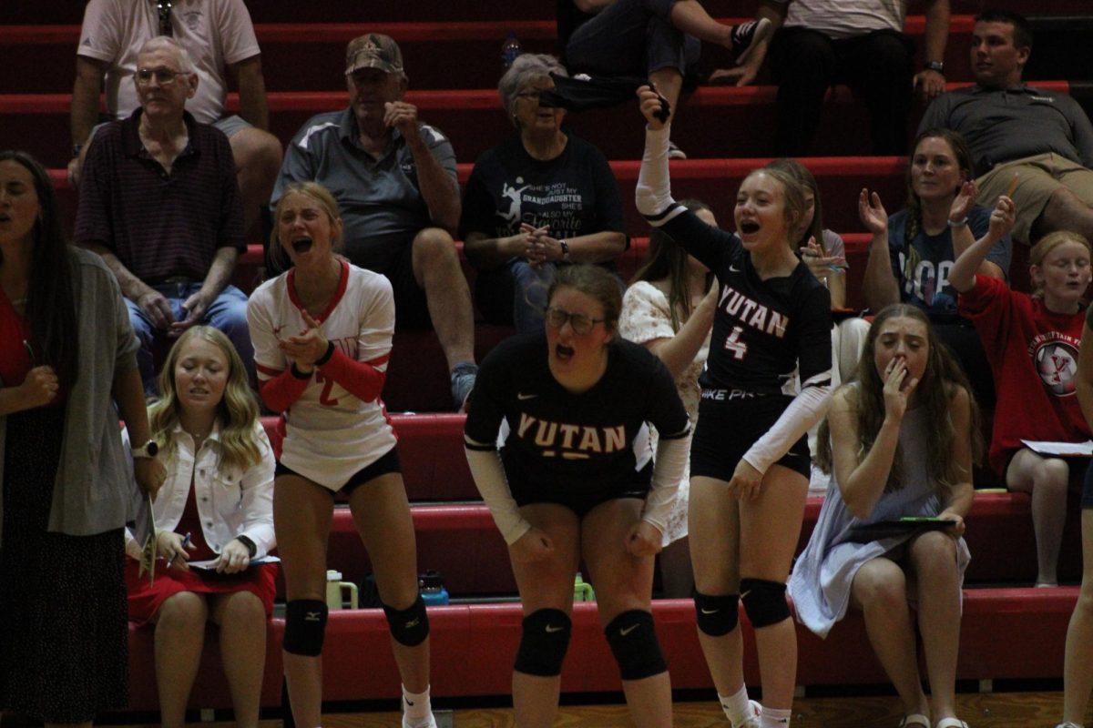 Freshman Emmy Tederman, senior Reagan Wilson, and  sophomore Kylie Krajicek stand up and cheer after a point. Wilson  has participated in volleyball for three years.