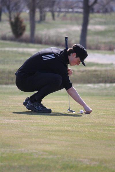Senior Connor North kneels down to line up his next shot. North placed fifth at the conference meet last year.
