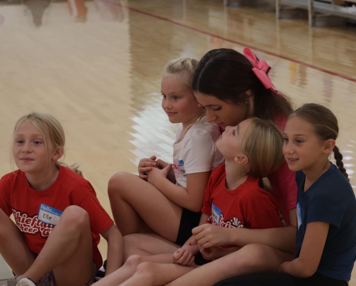 Freshman Anna Peterson sitting with some of the cheer camp girls. "This was my favorite part of the camp, they all came running up to me; it was so cute!" Peterson said.