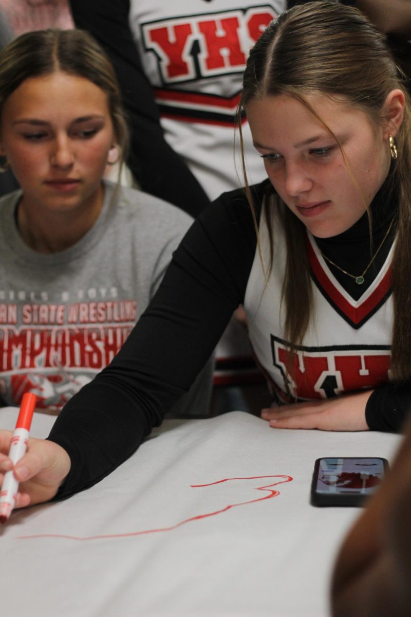 Sophomore Ella Henkel draws a chieftain head on her class poster. The rest of the class signed their names on the poster.