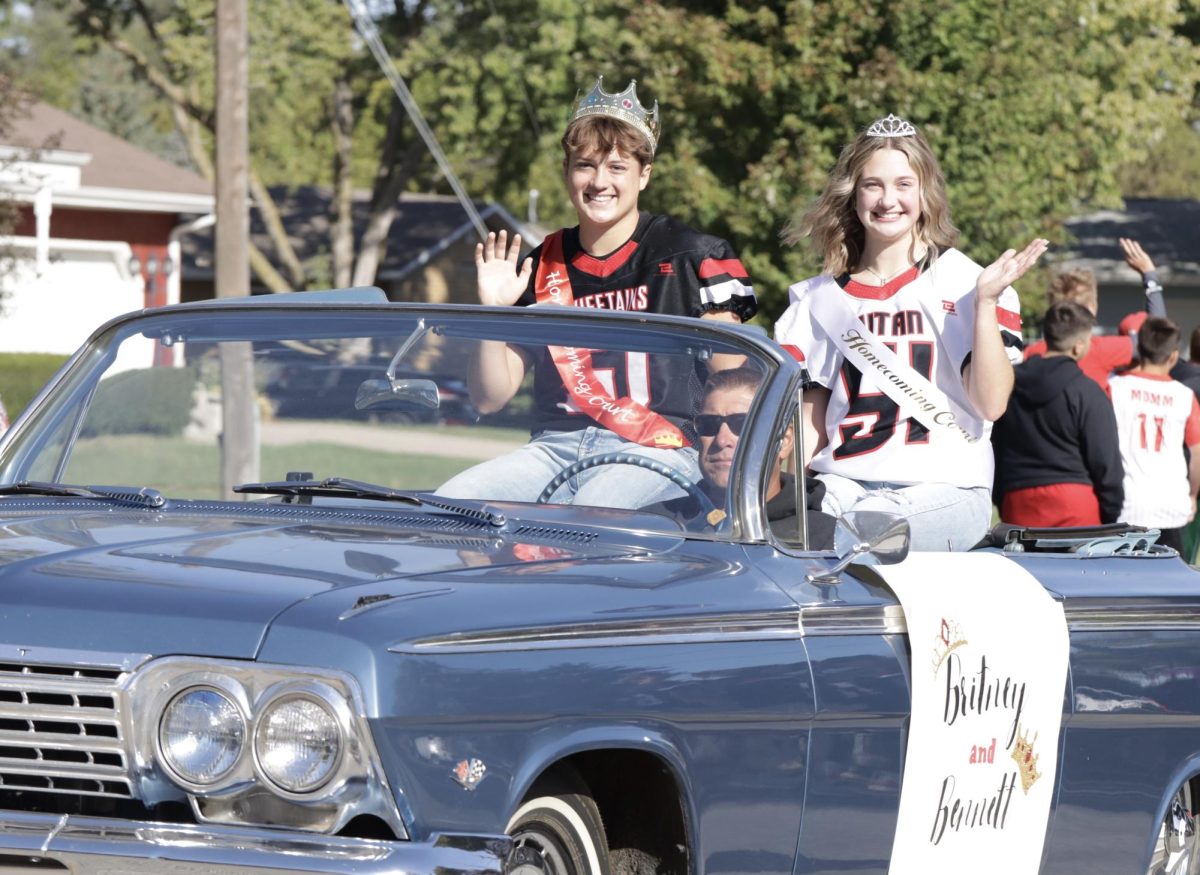 Seniors Bennett Ella and Britney Zeleny wave to the parade watchers. Zeleny's father, Gary Zeleny, drove their parade vehicle.