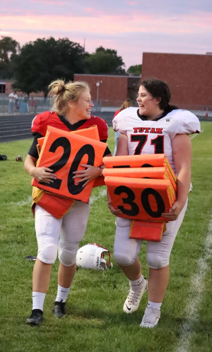 junior Haley Kube and freshman Jenna Trent help clean up the field after a game during the 2022 season. Kube and Trent were the only two girls on the team that year.