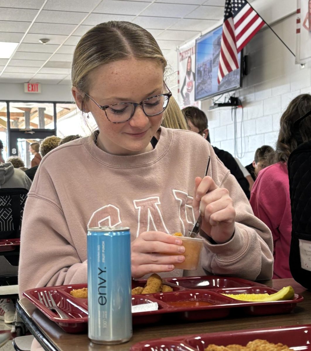 Sophomore Lexi Engel stirs her peach cup with her Envy drink at her side. The school offers three flavors of the 100 percent juice.