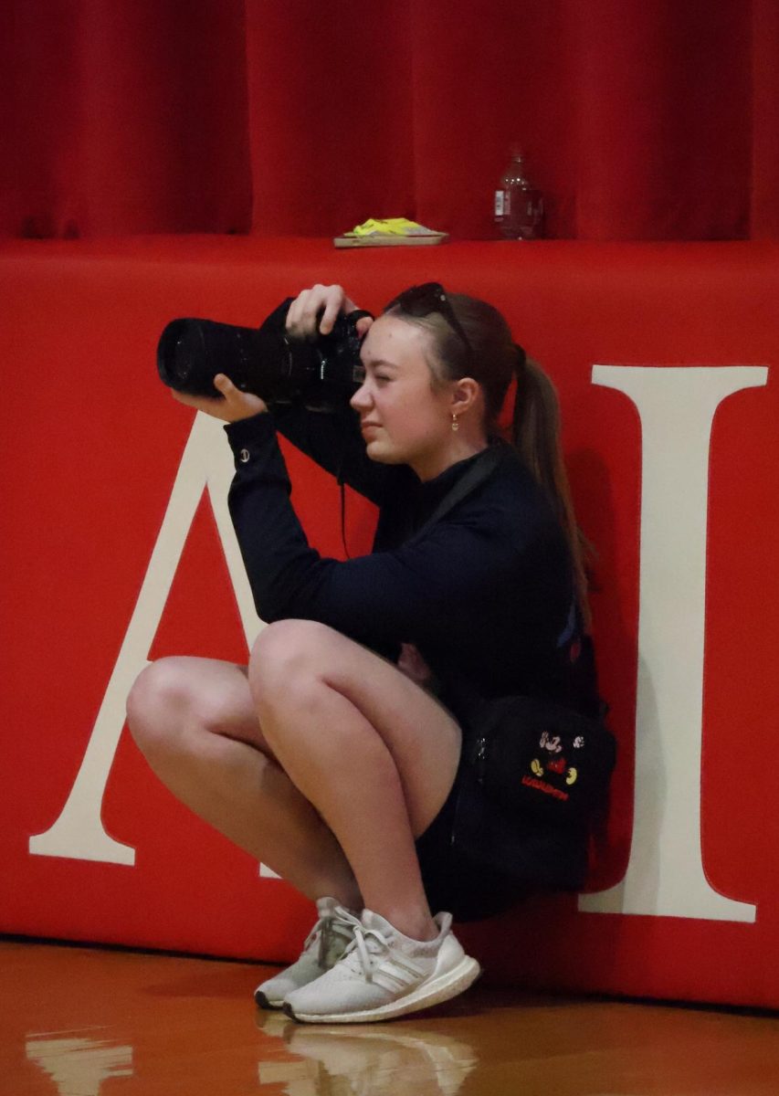 During the Yutan girls basketball game, junior Kylie Krajicek crouches to get the best angle for her photos. Krajicek also uses Instagram to post her pictures at kkrajicek.media.