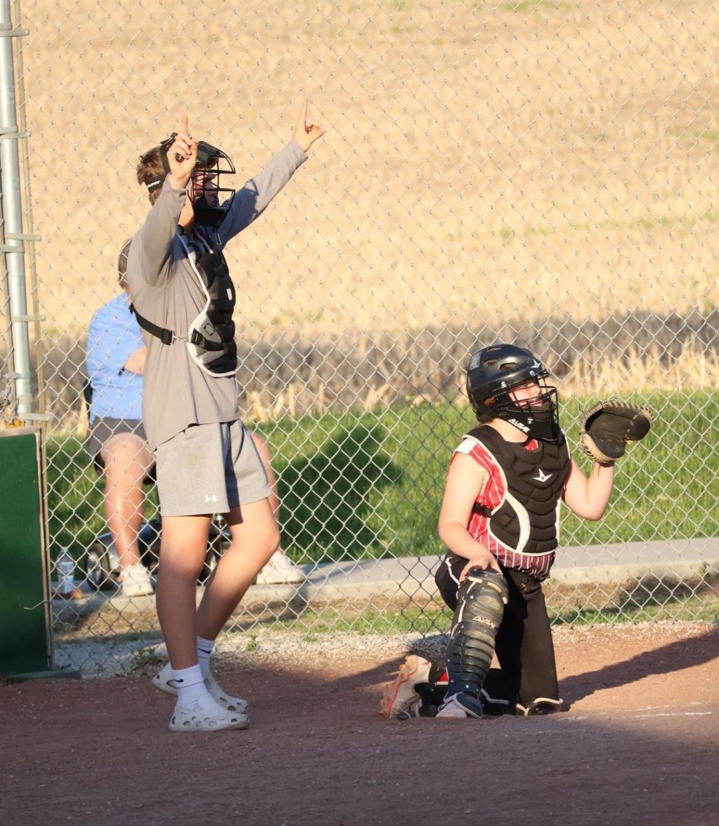Jakob Sieburg shows the batter's count during a 10U Yutan softball game . Sieburg umpired for his this league the most because his sisters were on the team.
