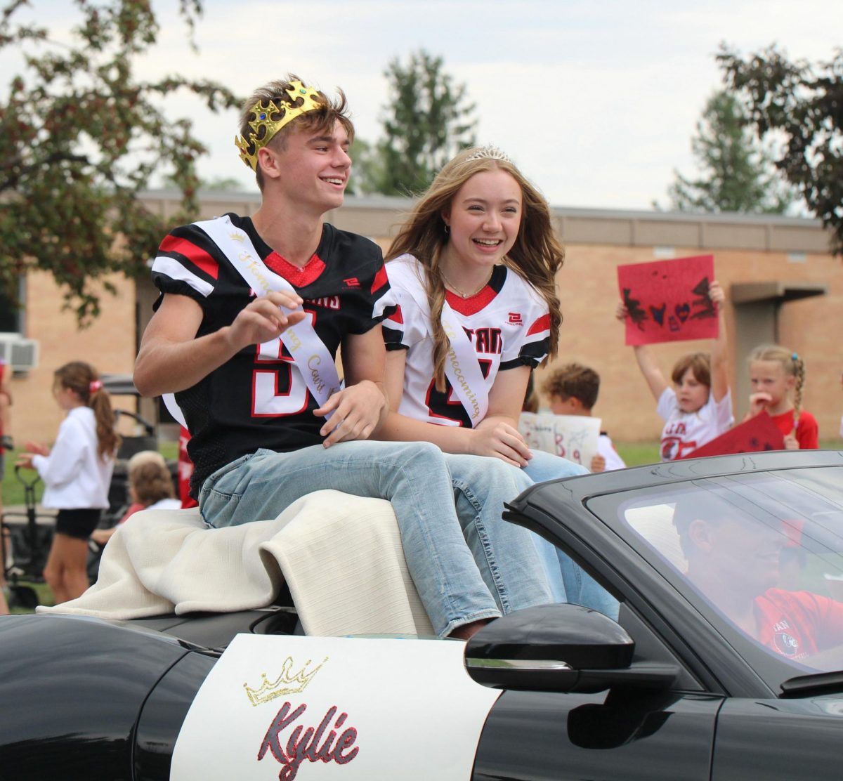 During the parade, senior homecoming court candidates Maddox Wentworth and Kylie Krajicek laugh while waving to the elementary students. Both candidates had older siblings who were on homecoming court. “I was laughing so hard because of Maddox saying funny dialogue the whole time,” Krajicek said.