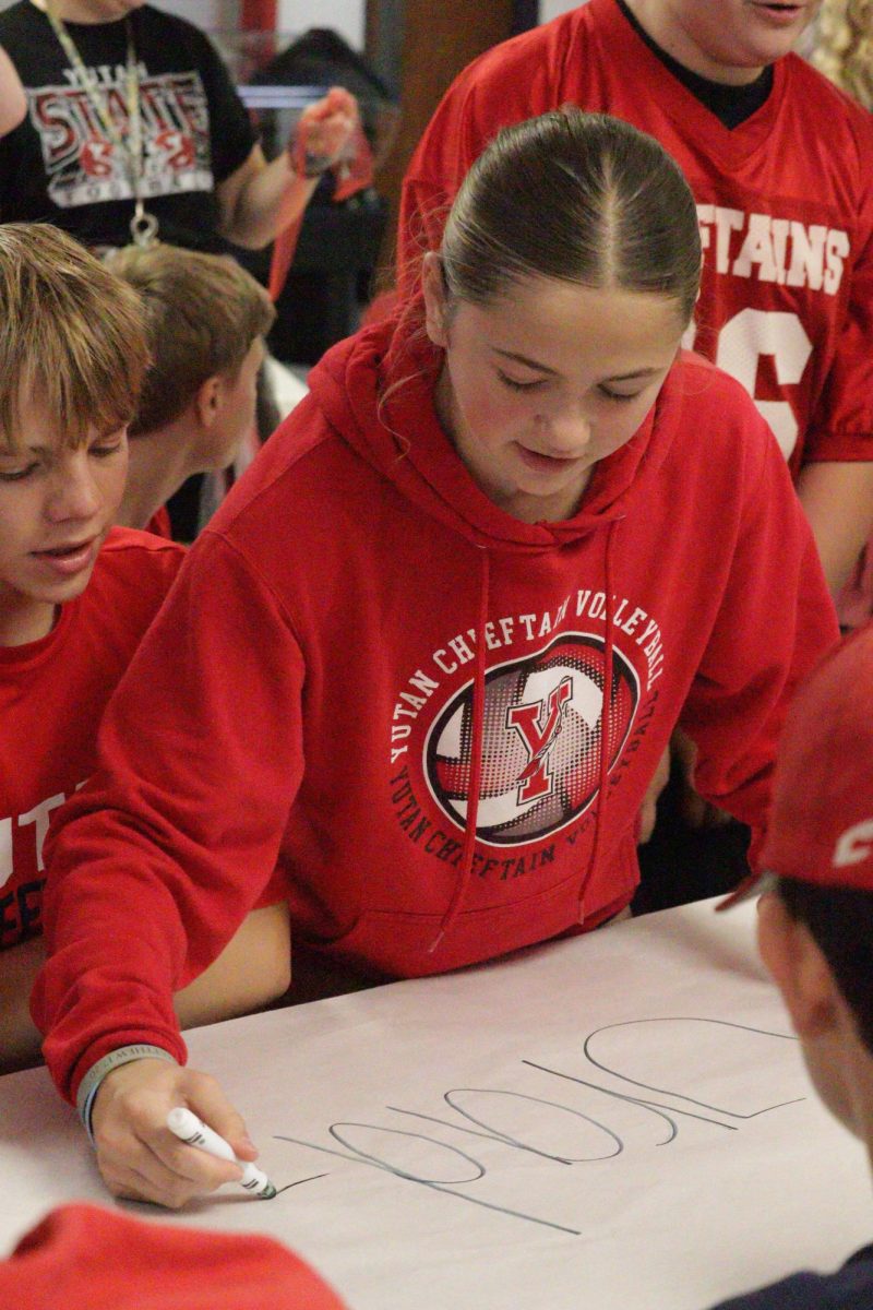 Seventh grader Maggie Zeleny writes on a banner for one of the rotational games. The seventh grade was paired up with the eighth grade for rotational games.