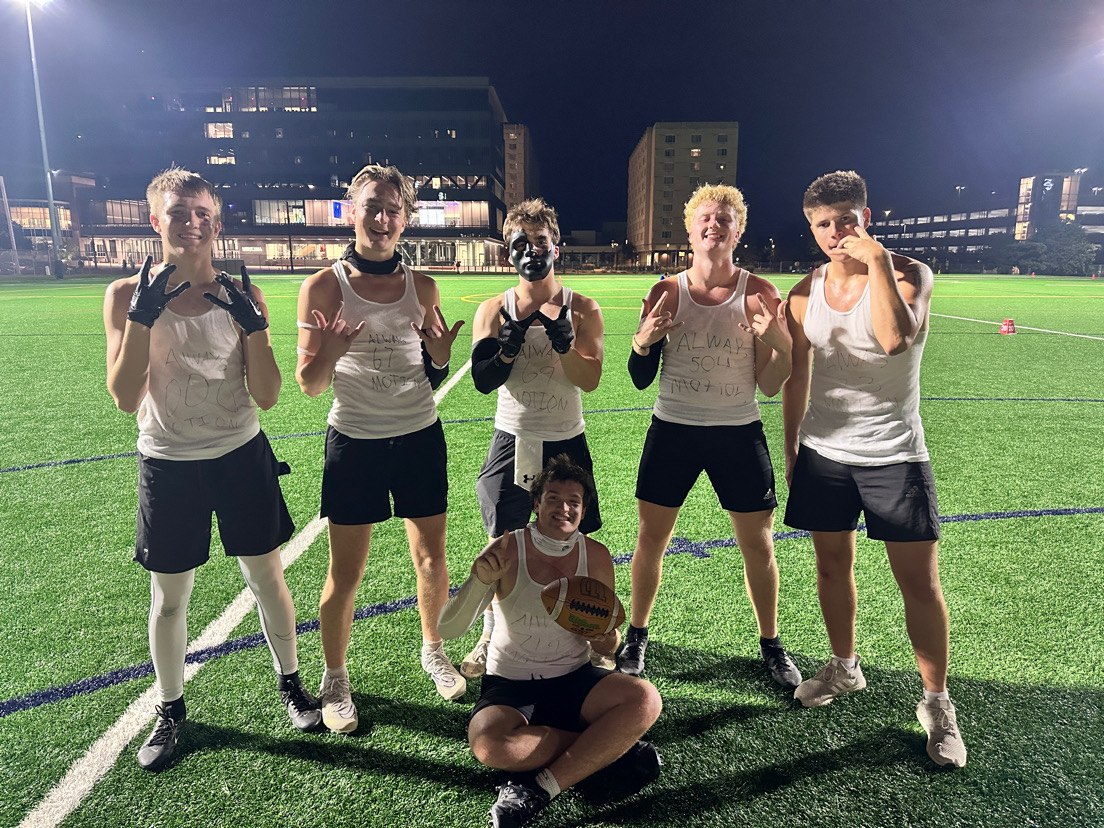 Drew Krajicek (far left) and AJ Arensberg (second from the right) pose with four of their teammates on an intramural field. Each player came up with a number to go with their team name, "Always Motion."