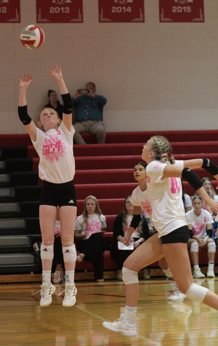 Freshman Ava Frye sets up Sophomore Jersey Daniels for a hit. Their pink out game was a triangular that they won against Raymond Central and Crete.